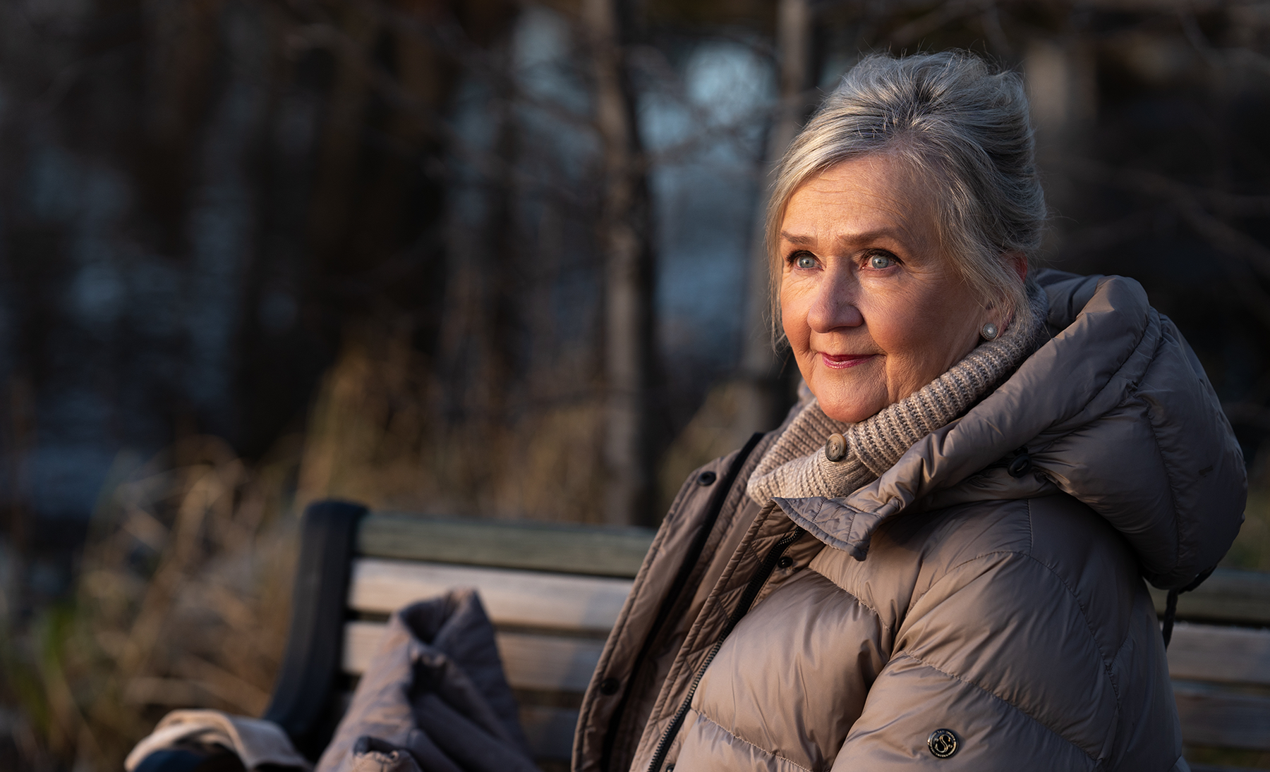 vanhempi nainen istuu ulkona penkillä